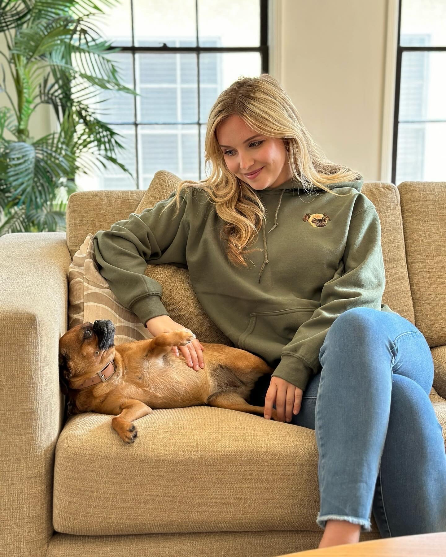 West & Willow lifestyle campaign — olive green hoodie, Keke relaxing for a belly rub on the couch