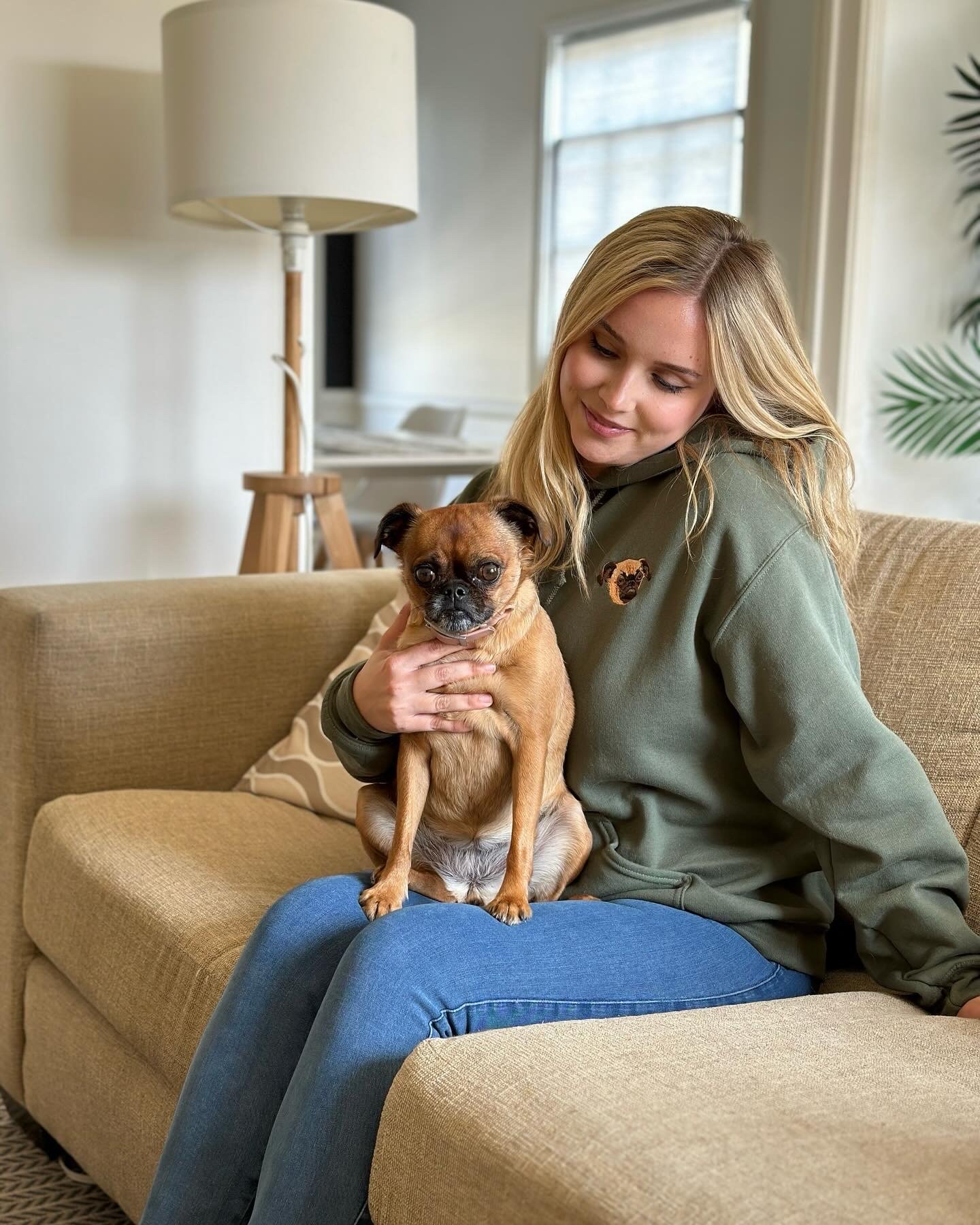 West & Willow lifestyle campaign — olive green hoodie embroidered with Keke's portrait, Keke standing on Jessica's lap